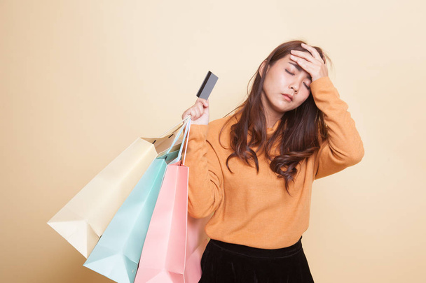 unglückliche junge Asiatin mit Einkaufstaschen und Kreditkarte. - Foto, Bild