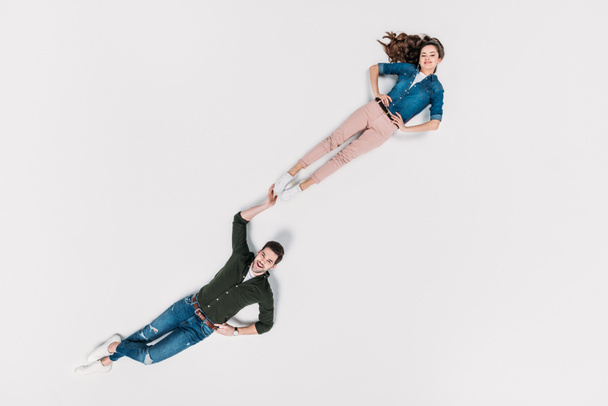 top view of stylish man carrying his girlfriend with one hand isolated on white - Φωτογραφία, εικόνα
