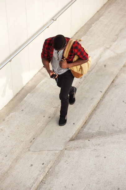 Bovenaanzicht portret jonge man lopen met de tas en mobiele telefoon - Foto, afbeelding