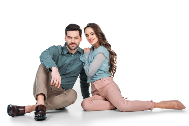 attractive young couple sitting on floor on white - Фото, зображення