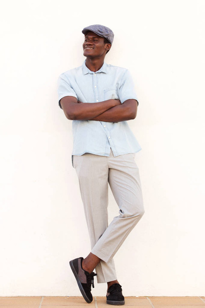 Hűvös afrikai fiatalember támaszkodva fehér fal keresztbe a teljes hosszúságú portréja - Fotó, kép