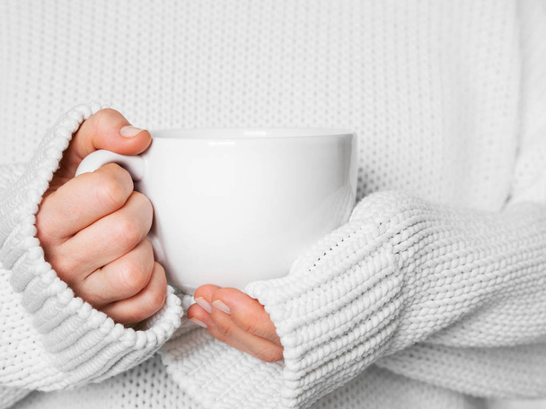Woman in warm white sweater holding white mug in hands - Fotografie, Obrázek