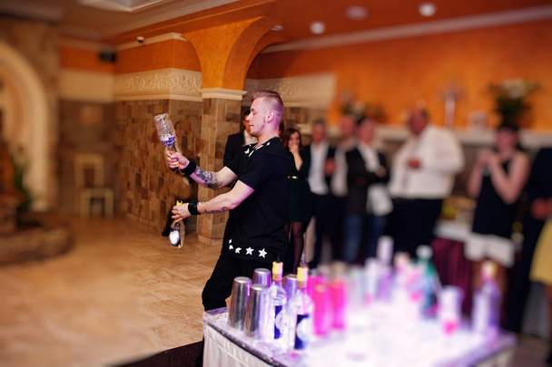 Talented bartender performing tricks with bottles and glasses in - Fotografie, Obrázek