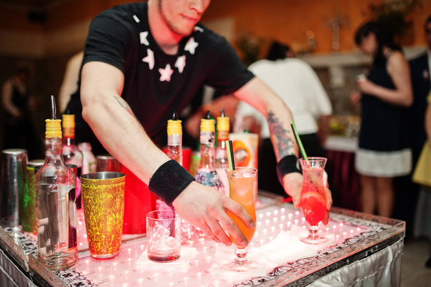 Getalenteerde barman uitvoeren van trucs met flessen en glazen in - Foto, afbeelding