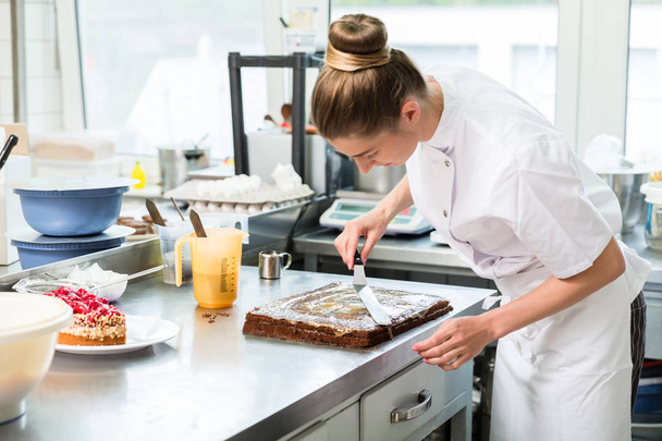 Cukiernik kobieta przygotowuje ciasto czekoladowe z polewa - Zdjęcie, obraz
