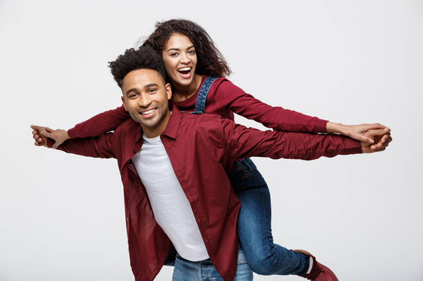 Close-up young african american couple riding back and playing like plane. - 写真・画像