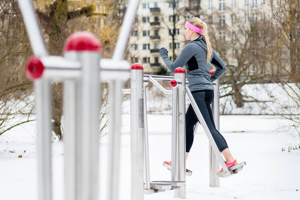 Kış günü parkta spor yolunda bacaklarını çalıştıran genç bir kadın. - Fotoğraf, Görsel