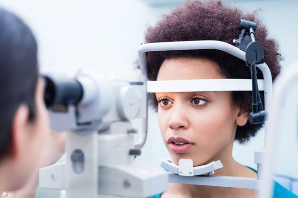 Optician medindo olhos de mulher com refratômetro em loja de óptica
 - Foto, Imagem