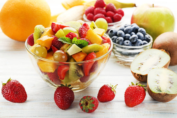 Salada de frutas em tigela na mesa de madeira branca
 - Foto, Imagem