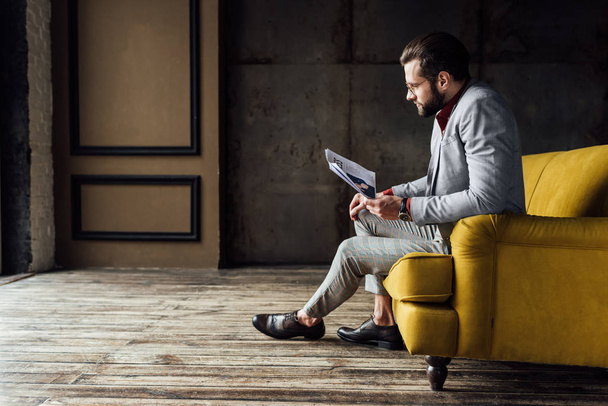 fashionable man reading newspaper and sitting on couch  - Foto, Imagem