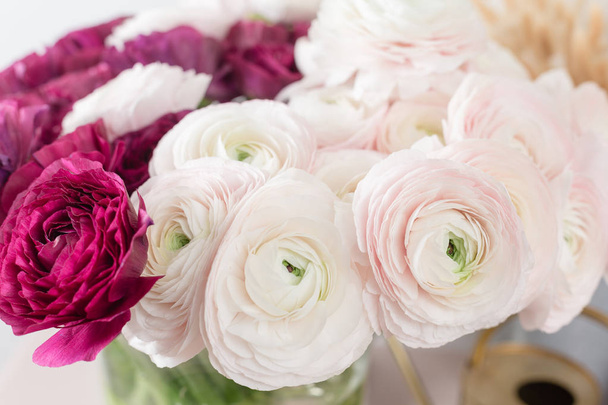 Περσικά-νεραγκούλα. Ματσάκι πολύχρωμο και απαλό ροζ ranunculus λουλούδια ανοιχτό φόντο. Γυάλινο βάζο σε ροζ vintage ξύλινο τραπέζι. Ταπετσαρία - Φωτογραφία, εικόνα