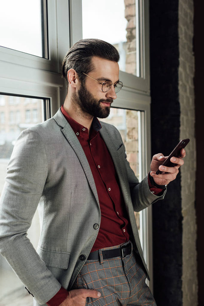 stylish handsome man in formal wear using smartphone at window  - Zdjęcie, obraz