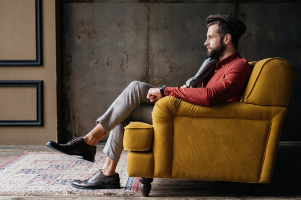 fashionable bearded man sitting on yellow sofa - Zdjęcie, obraz