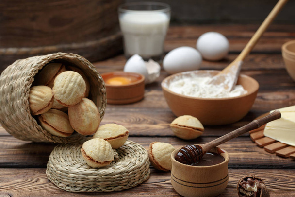 galletas caseras en forma de nueces con leche condensada hervida crema en la mesa de madera
. - Foto, Imagen
