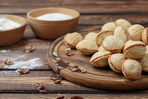 hausgemachte Kekse geformte Nüsse mit Sahne gekochte Kondensmilch auf Holztisch. - Foto, Bild