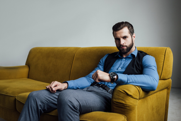 stylish elegant man sitting on yellow sofa   - Foto, Bild