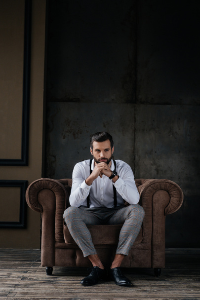 handsome stylish man thinking and sitting in armchair - Фото, зображення