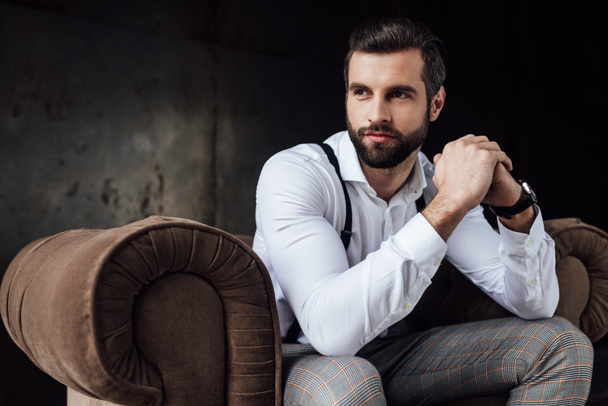handsome bearded man thinking and sitting in armchair  - Photo, Image