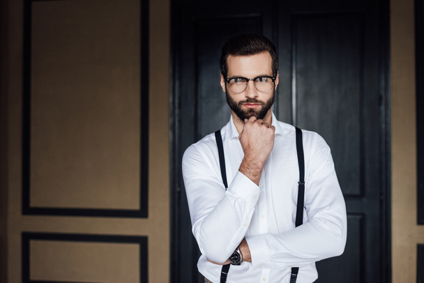thoughtful elegant man posing in white shirt and suspenders  - Фото, зображення