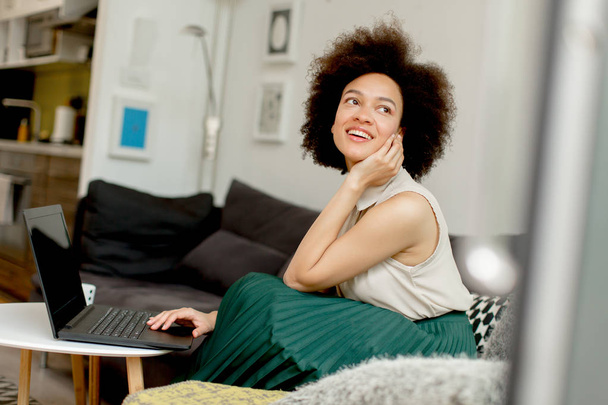 Mladá africká americká žena s přenosným počítačem v obývací pokoj doma - Fotografie, Obrázek