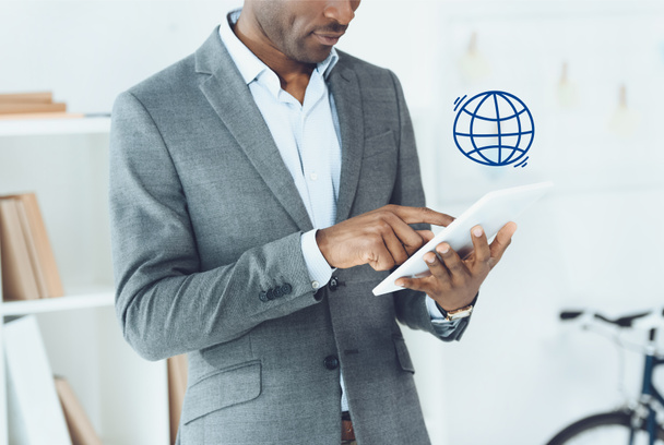 cropped image of african american man using digital tablet and globe symbol - Foto, imagen