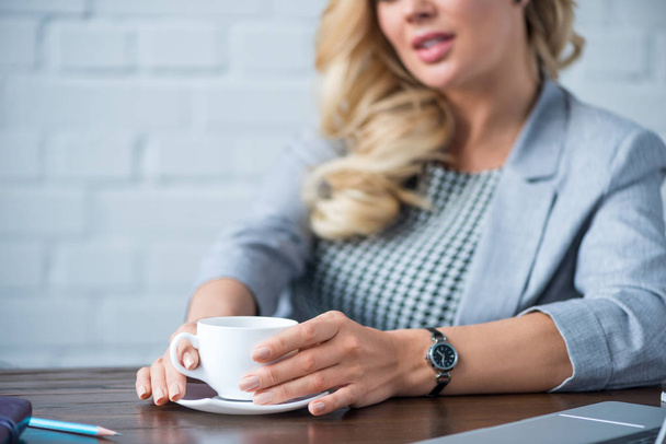 image recadrée de femme d'affaires tenant tasse de café au bureau
 - Photo, image