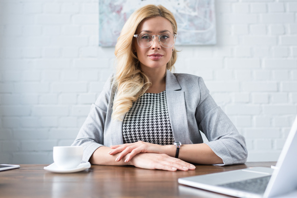 beautiful businesswoman sitting at table in office and looking at camera - Foto, Imagem