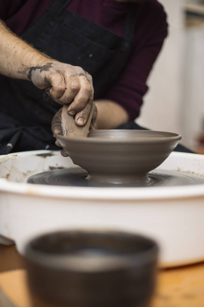 Vista de detalhe de perto em um artista faz cerâmica de barro em uma roda de giro
 - Foto, Imagem
