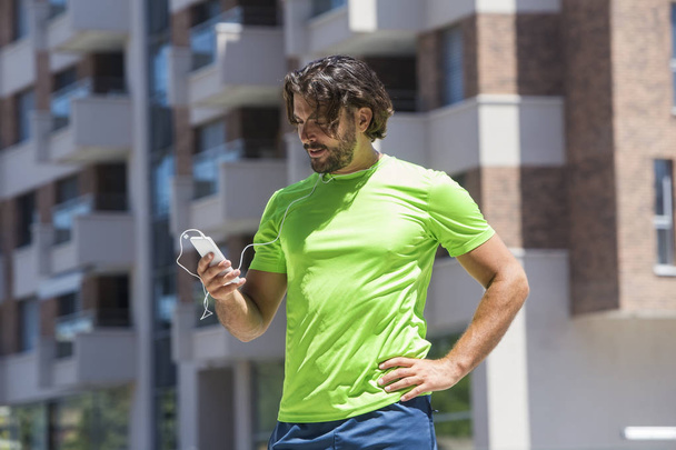 Muotokuva mies juoksija käyttäen matkapuhelin ulkona
 - Valokuva, kuva