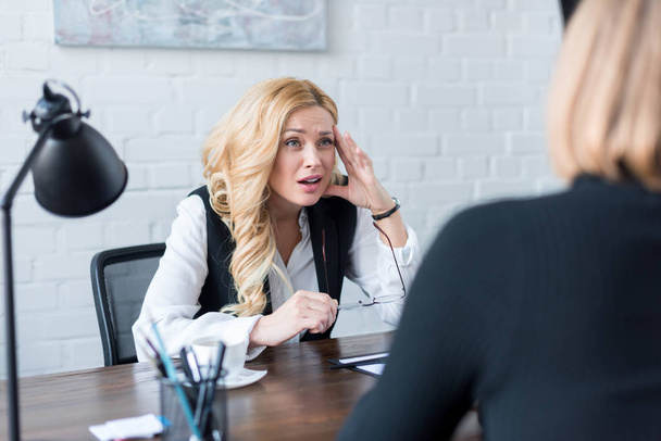 irritated businesswoman looking at coworker in office - Foto, Bild