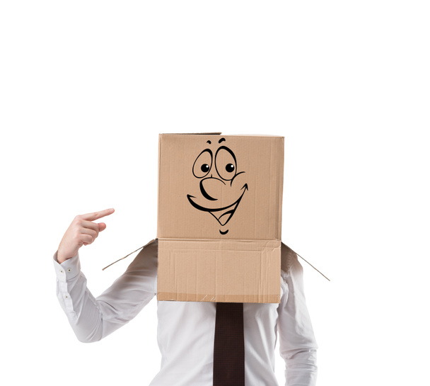 fröhlicher Geschäftsmann zeigt auf Pappschachtel auf seinem Kopf isoliert auf weiß - Foto, Bild