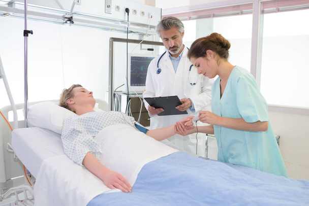 doctor examining female patient lying on bed in hospital - Valokuva, kuva