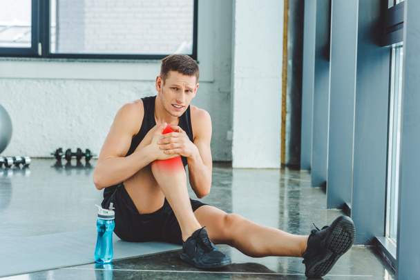 sportif avec genou blessé reposant sur le tapis dans la salle de gym
 - Photo, image