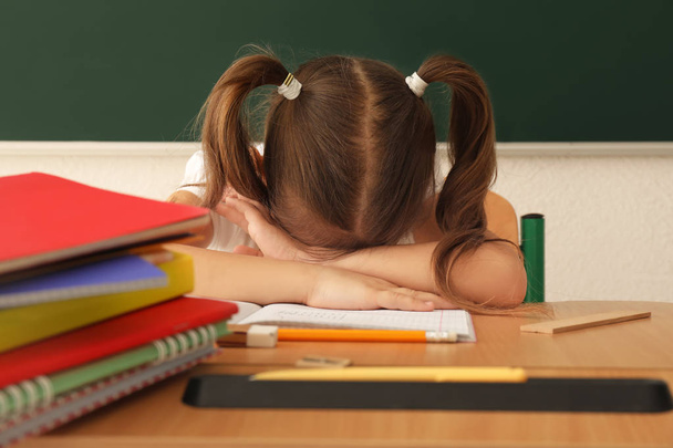 Sleeping little girl tired of doing homework in classroom - Φωτογραφία, εικόνα