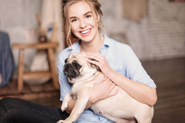 Young woman with cute pug dog at home. Pet adoption - Fotoğraf, Görsel