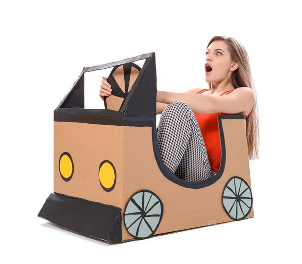 Young woman playing with cardboard auto against white background. Concept of buying new car - Zdjęcie, obraz