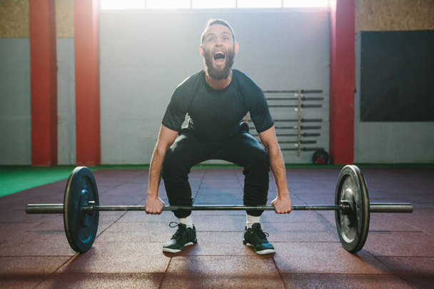 Atleet man met een baard uitoefenen in een crossfit fitnessruimte - Foto, afbeelding