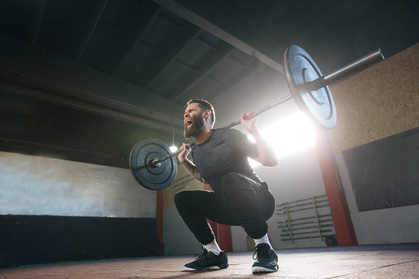 Athlete man with a beard exercising in a crossfit gym - Photo, Image
