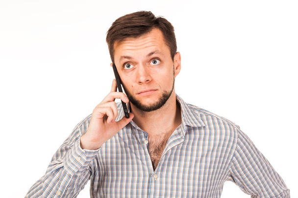 The bearded man is talking on the phone. Posing with different emotions. Simulation of conversation. Isolated photo on the white background.  Dressed in a shirt  - Foto, afbeelding