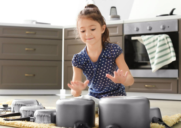 Cute little girl playing with kitchenware as drums in kitchen - Foto, Imagem
