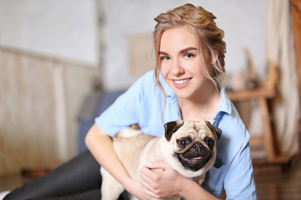 Young woman with cute pug dog at home. Pet adoption - Фото, зображення