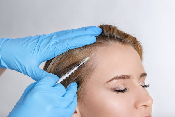 Young woman with hair problem receiving injection on light background, closeup - Φωτογραφία, εικόνα