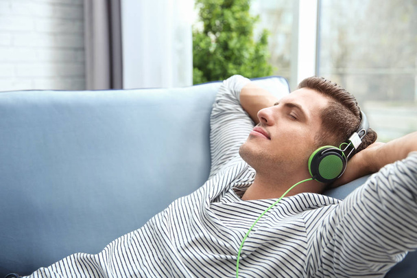 Relaxed young man listening to music at home - Foto, afbeelding