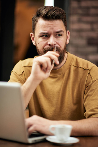 Uomo che utilizza laptop e smartphone mentre seduto in un caffè. Nuove tecnologie
 - Foto, immagini