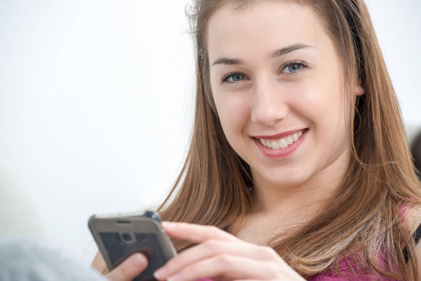 young and smiling woman using smartphone at home - Foto, imagen