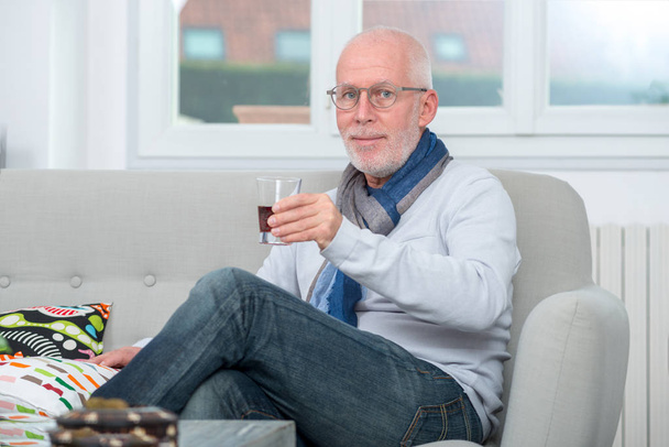 mature man drinking glass of alcohol at home - Фото, зображення