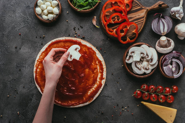 oříznutý snímek ženy dávat houbové řezy na pizza těsto na pizzu na konkrétní tabulce - Fotografie, Obrázek