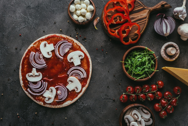 top view of unprepared pizza with ingredients on concrete surface - Fotó, kép