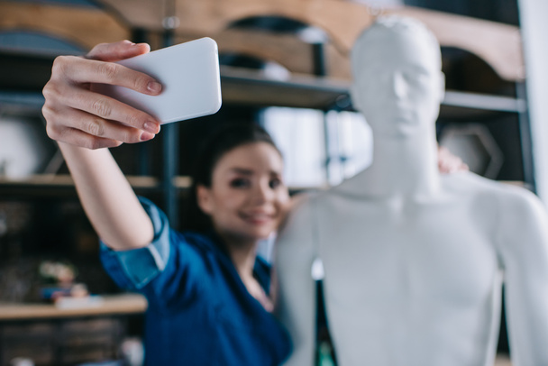 selective focus of smiling woman taking selfie together with mannequin, perfect relationship dream concept - Photo, Image