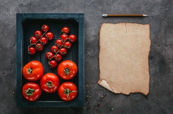 vista superior de tomates en caja y papel en blanco sobre superficie de hormigón
 - Foto, Imagen